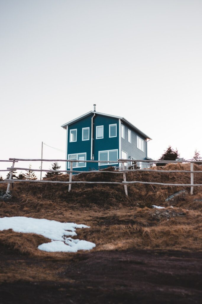 Zu sehen ist ein eher nordisches Haus im Stil einer Stadtvilla, aber in freiem, hügeligen Gelände gelegen. Oft sind es diese speziellen Immobilien, für die ein Wert ermittelt werden muss. Dafür wird ein Immobiliengutachten nach § 194 BauGB angefertigt.